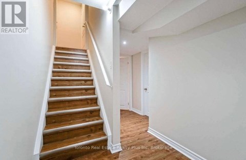 A staircase in a house with a brokerage logo on the wall.