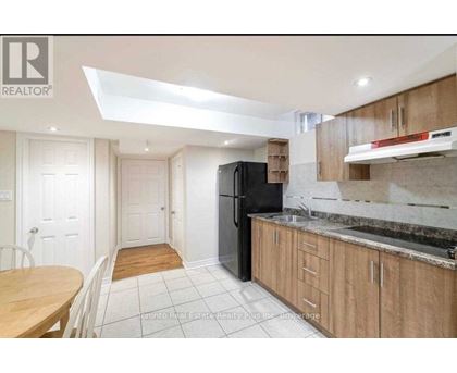 A kitchen with a black fridge and wooden cabinets.