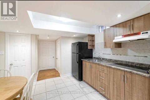 A kitchen with a black fridge and wooden cabinets.