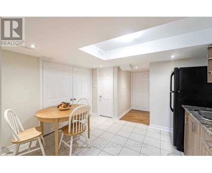 A kitchen with a table and chairs in the foreground and a refrigerator in the background.