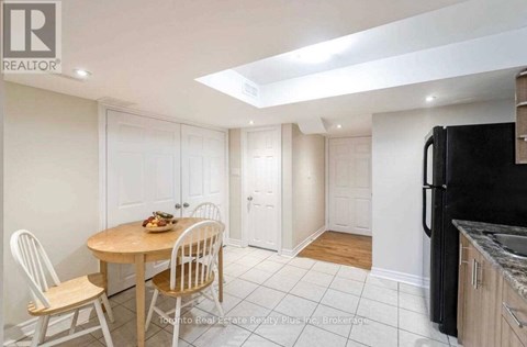 A kitchen with a table and chairs in the foreground and a refrigerator in the background.