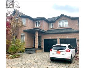 A white car is parked in front of a brick house.