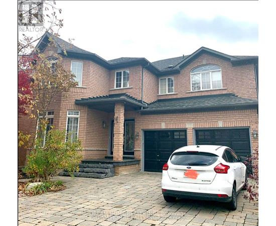A white car is parked in front of a brick house.