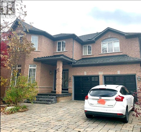 A white car is parked in front of a brick house.