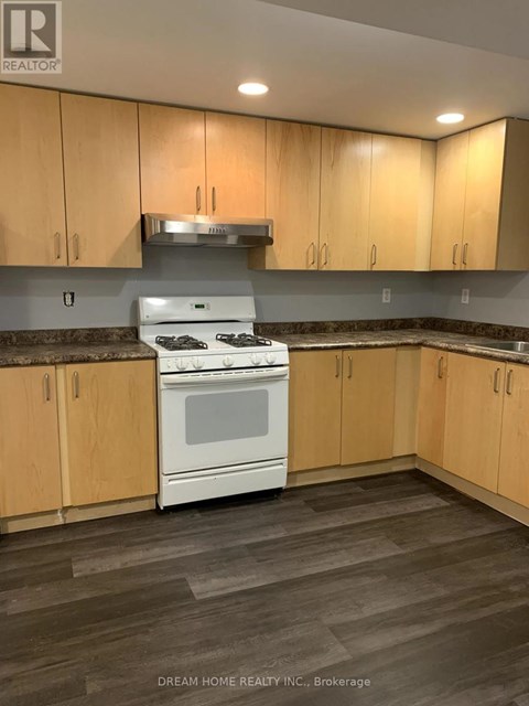 A kitchen with wooden cabinets and a white stove top oven.