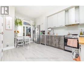 A kitchen with white cabinets and a wooden floor.