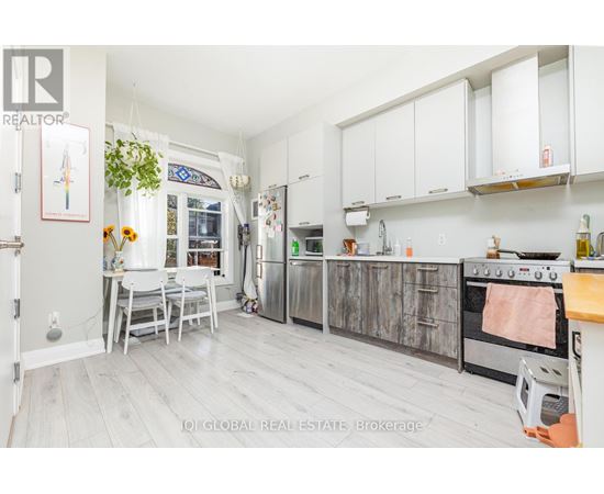 A kitchen with white cabinets and a wooden floor.