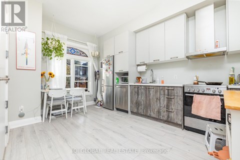 A kitchen with white cabinets and a wooden floor.