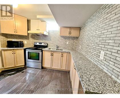 A kitchen with wooden cabinets and a brick wall.