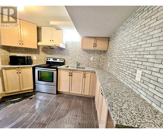 A kitchen with wooden cabinets and a brick wall.