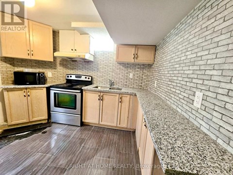 A kitchen with wooden cabinets and a brick wall.