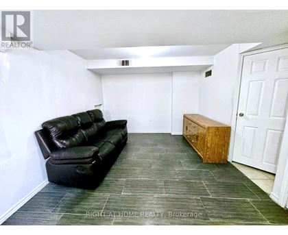 A black leather sofa sits in a white room with a wooden bench.