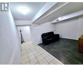 A black leather couch sits in a white room with a wooden bench.