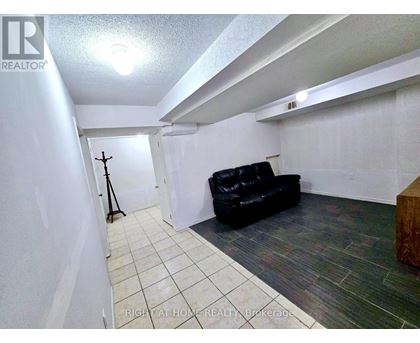 A black leather couch sits in a white room with a wooden bench.