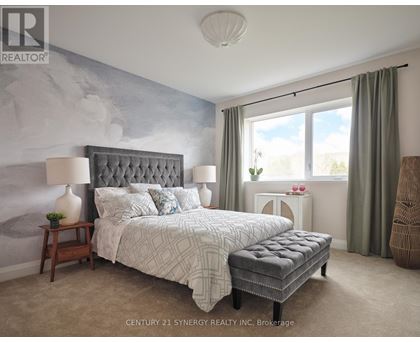 A bedroom with a large bed and a grey tufted headboard.