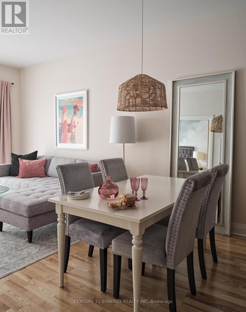 A dining room with a grey sofa, a white table and chairs, and a painting on the wall.