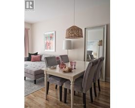 A dining room with a grey sofa, a white table and chairs, and a painting on the wall.