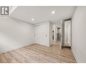 A room with wooden flooring and white walls, with a door leading to another room.