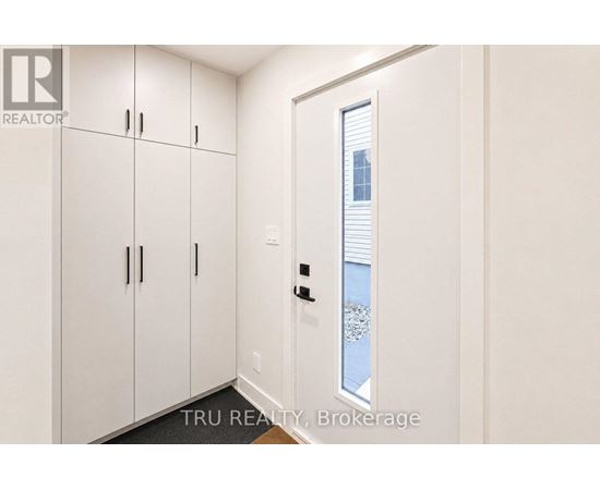 A white door with a window in the middle of a white wall.