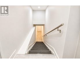 A staircase with a metal railing and wooden steps leading to a light at the end.