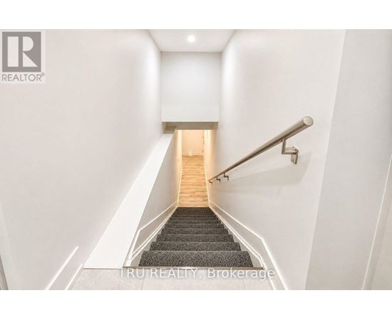 A staircase with a metal railing and wooden steps leading to a light at the end.