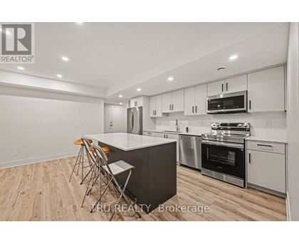 A modern kitchen with wooden flooring and stainless steel appliances.