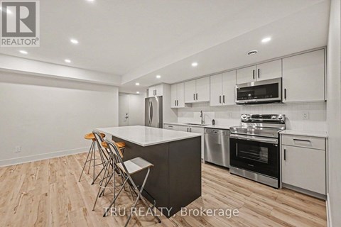 A modern kitchen with wooden flooring and stainless steel appliances.