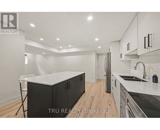 A modern kitchen with a white countertop and black cabinets.
