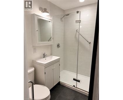 A white bathroom with a toilet, sink, and shower.
