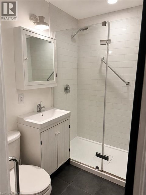 A white bathroom with a toilet, sink, and shower.