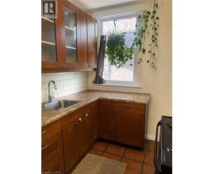 A kitchen with brown cabinets and a black dishwasher.