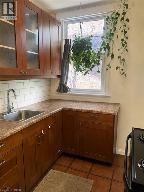 A kitchen with brown cabinets and a black dishwasher.