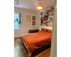 A bedroom with a bed, a window, and a shelf with various items.