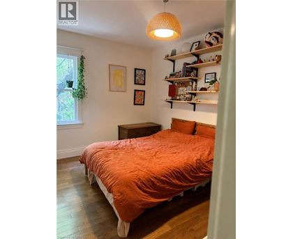 A bedroom with a bed, a window, and a shelf with various items.