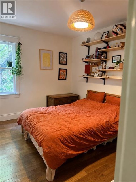 A bedroom with a bed, a window, and a shelf with various items.