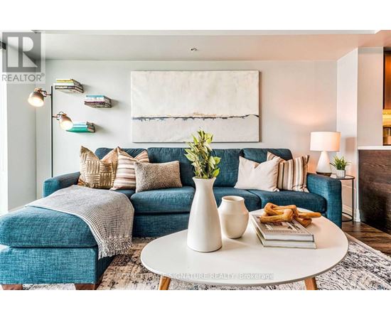 A living room with a blue couch, a white coffee table, and a painting on the wall.