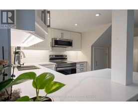 A modern kitchen with a white countertop and stainless steel appliances.