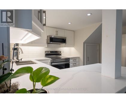 A modern kitchen with a white countertop and stainless steel appliances.