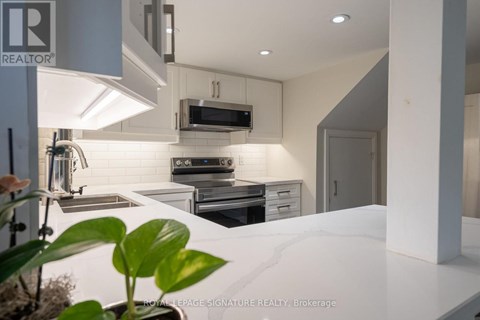 A modern kitchen with a white countertop and stainless steel appliances.