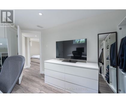 A modern bedroom with a white dresser and a flat screen TV.