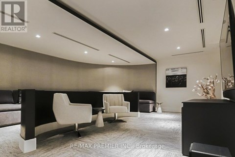 A modern living room with a black sofa and white chairs.
