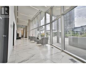 A hallway with a marble floor and glass walls leading to an outdoor area.