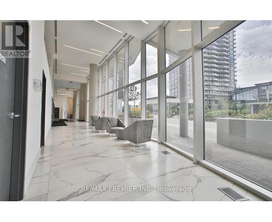 A hallway with a marble floor and glass walls leading to an outdoor area.
