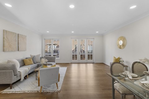 A modern living room with a grey sofa and a glass dining table.