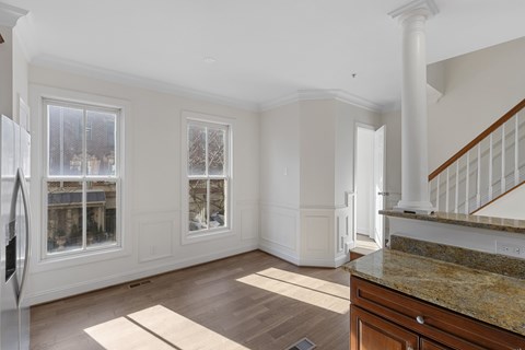 A kitchen with a refrigerator on the left and a staircase on the right.