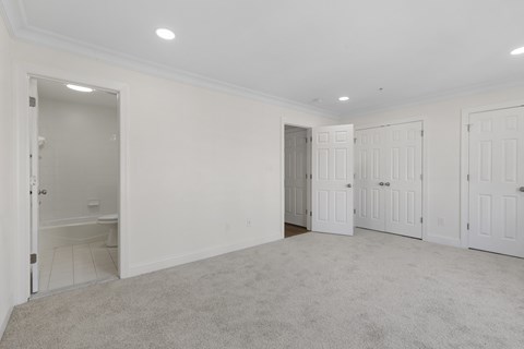 A spacious room with white walls and carpeted floor.