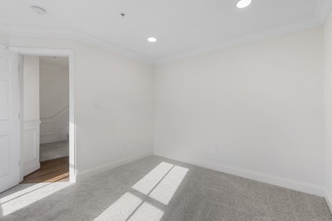 A spacious room with white walls and a carpeted floor.