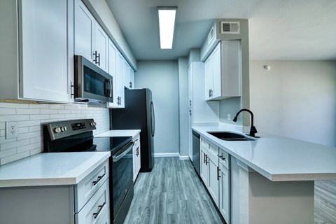 A modern kitchen with a black refrigerator and white countertops.