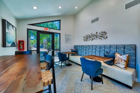 A modern living room with a wooden table and blue chairs.