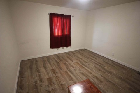 A room with a wooden floor and a red curtain.